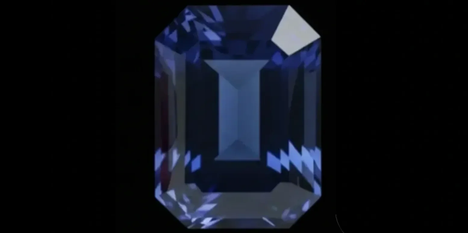 Close-up of a deep blue emerald-cut gemstone on black background.